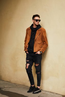 Model görünümlü bir adam duvara yakın dur ve onun gözlük savaşa tutun