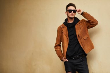 Model görünümlü bir adam duvara yakın dur ve onun gözlük savaşa tutun