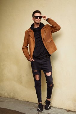 Model görünümlü bir adam duvara yakın dur ve onun gözlük savaşa tutun