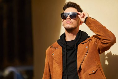 Model görünümlü bir adam duvara yakın dur ve onun gözlük savaşa tutun