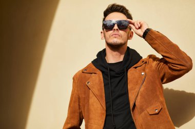 Model görünümlü bir adam duvara yakın dur ve onun gözlük savaşa tutun