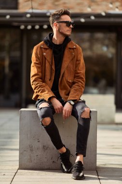 Model görünümlü bir adam oturup modern park arka planda, bankta lo