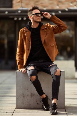 Model görünümlü bir adam oturup modern park arka planda, bankta lo