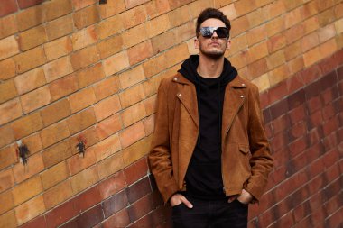 Model görünümlü bir adam duvara yakın dur ve onun gözlük savaşa tutun