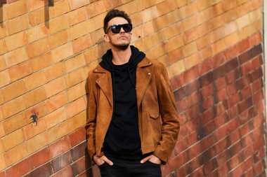 Model görünümlü bir adam duvara yakın dur ve onun gözlük savaşa tutun