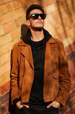 Model görünümlü bir adam duvara yakın dur ve onun gözlük savaşa tutun