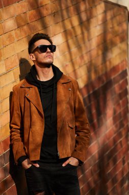 Model görünümlü bir adam duvara yakın dur ve onun gözlük savaşa tutun