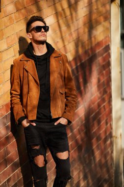 Model görünümlü bir adam duvara yakın dur ve onun gözlük savaşa tutun