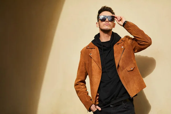 Model görünümlü bir adam duvara yakın dur ve onun gözlük savaşa tutun