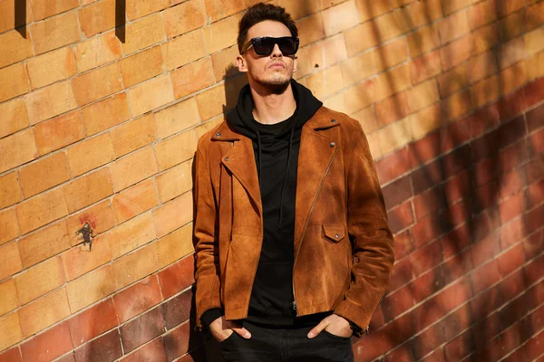 Model görünümlü bir adam duvara yakın dur ve onun gözlük savaşa tutun