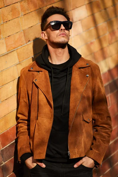 Model görünümlü bir adam duvara yakın dur ve onun gözlük savaşa tutun