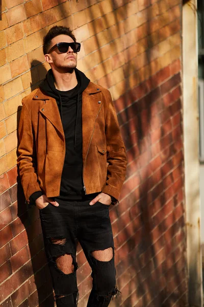 Model görünümlü bir adam duvara yakın dur ve onun gözlük savaşa tutun