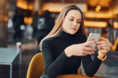 Kız oturup sandalye ve onun telefon bakmak