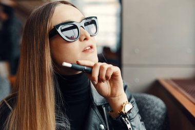 Kız sit caffee yerde ve duman elektronik sigara aşınma gla