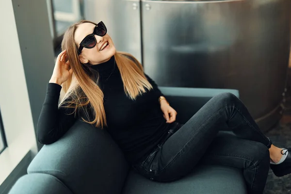 Giovane bella ragazza sedersi sul divano indossare occhiali e sorridere a venuto — Foto Stock