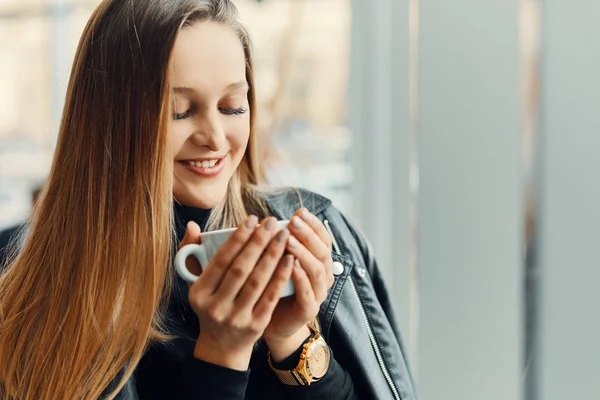 Güzel kız stand fincan kahve ve bir gülümseme ile pencere yakınındaki — Stok fotoğraf