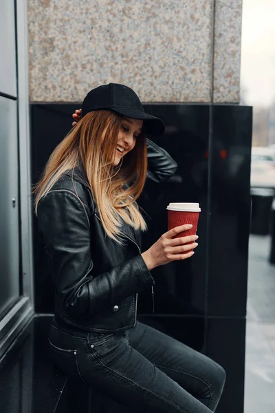 Jeune fille debout près du mur porter chapeau et verres et boire co — Photo