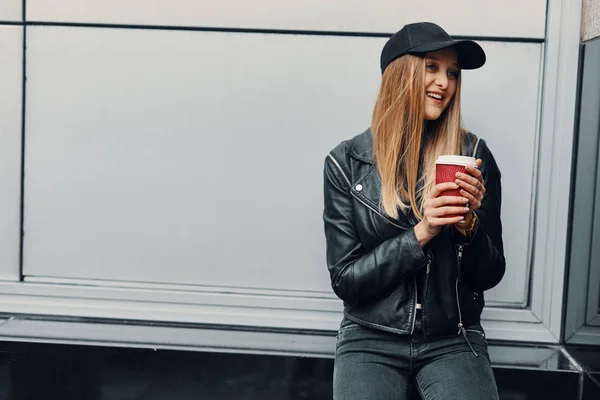 Jeune fille debout près du mur porter chapeau et verres et boire co — Photo