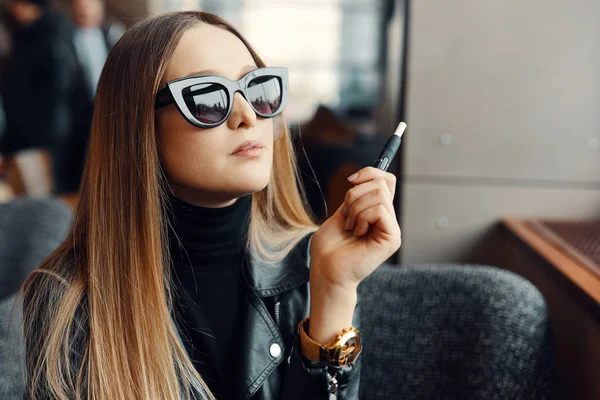 Menina sentar no lugar caffee e fumar cigarro eletrônico desgaste gla — Fotografia de Stock