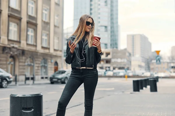 Chica bonita de pie en la calle escuchar música de sus auriculares — Foto de Stock