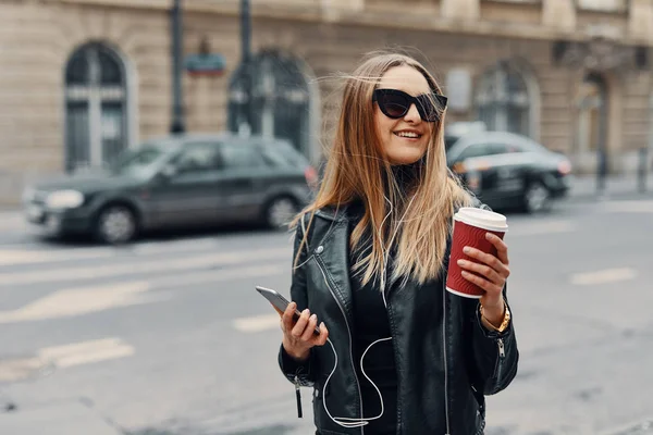 Chica bonita de pie en la calle escuchar música de sus auriculares — Foto de Stock