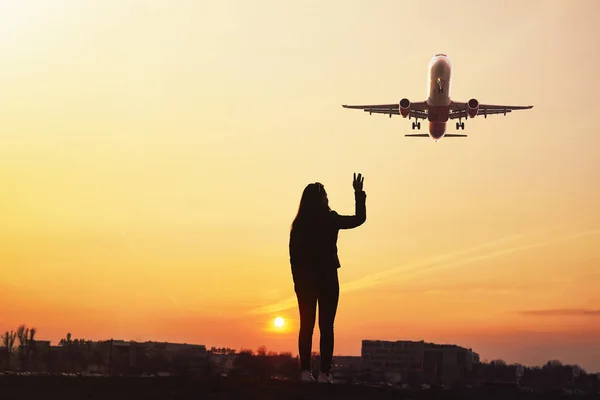 Girl wave to the plane with sunset background — Stock Photo, Image