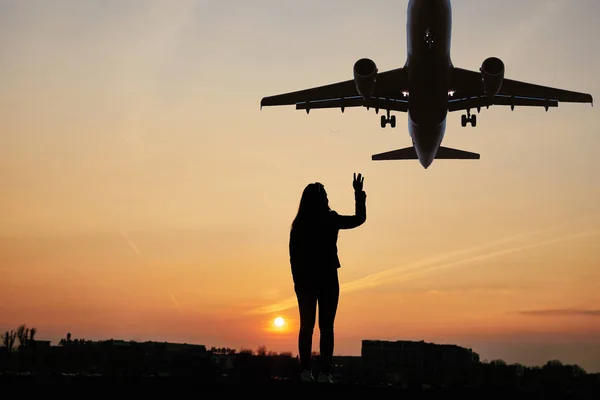 Girl wave to the plane with sunset background — Stock Photo, Image