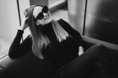 Genç güzel kız kanepede gözlük oturup geldi için gülümse