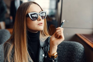 Kız sit caffee yerde ve duman elektronik sigara aşınma gla