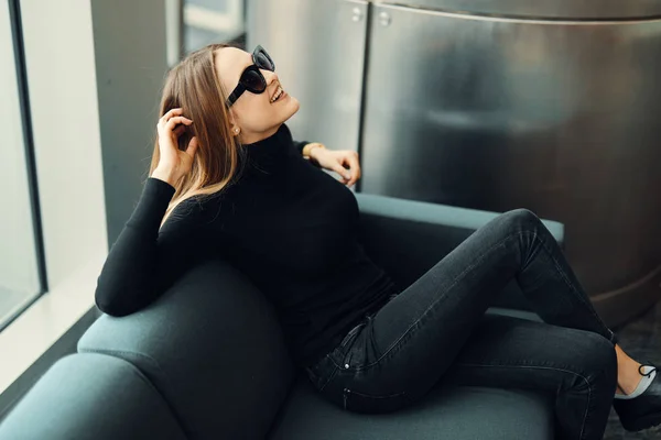 Giovane bella ragazza sedersi sul divano indossare occhiali e sorridere a venuto — Foto Stock