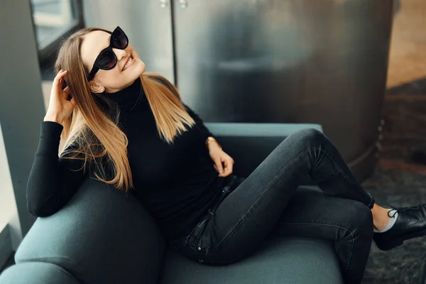Young pretty girl sit on the sofa wear glasses and smile to came — Stock Photo, Image