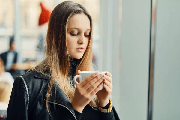 Mooi meisje stand in de buurt van het venster met kopje koffie en glimlach — Stockfoto