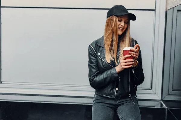 Jeune fille debout près du mur porter chapeau et verres et boire co — Photo