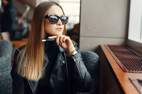 Flickan sitter i caffee plats och rök elektronisk cigarett slitage gla — Stockfoto