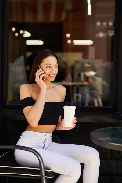 Pretty girl sit near coffee place and talk at her phone