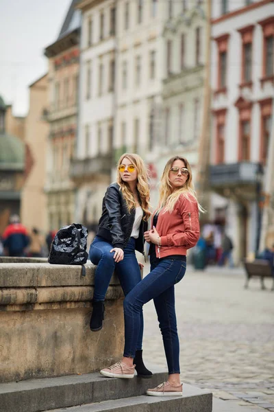 Duas raparigas sentam-se na fonte e falam umas com as outras. — Fotografia de Stock