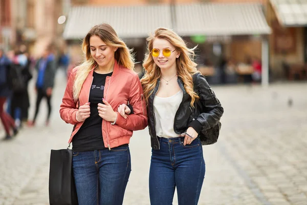 Dos chicas caminando por la calle de la ciudad y hablando entre ellas — Foto de Stock