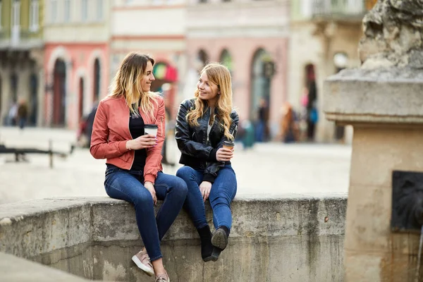 Dos chicas se sientan en la fuente y hablan entre ellas — Foto de Stock