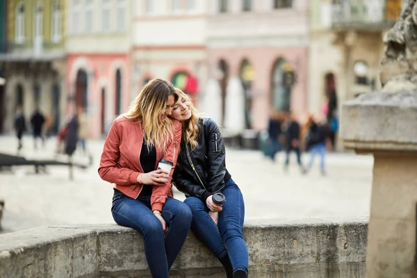 Duas raparigas sentam-se na fonte e falam umas com as outras. — Fotografia de Stock