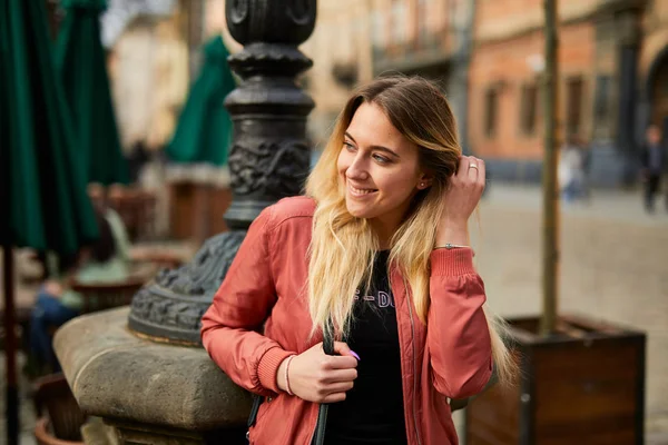 Kaunis tyttö poseeraa kaupungin kadulla ja hymyile kameralle — kuvapankkivalokuva