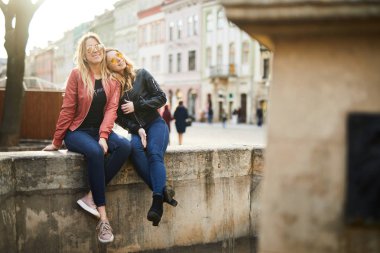 İki kız çeşme üzerinde oturup birbirleriyle konuşmak 