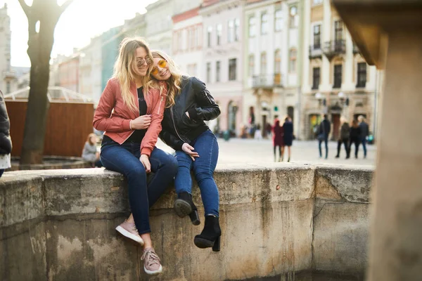 Две девушки сидят на фонтане и разговаривают друг с другом — стоковое фото