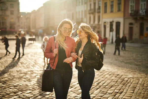 Two girls walking on the city street and talk to each other