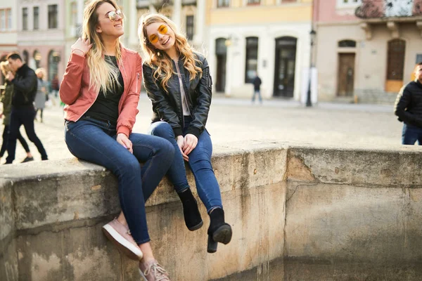 Zwei Mädchen sitzen auf dem Brunnen und reden miteinander — Stockfoto