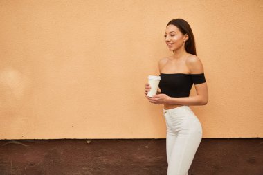 Güzel sportif kız duvara yakın duran ve kamera için poz,