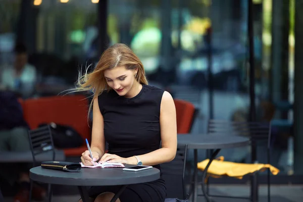 Piękna dziewczyna siedzi na stole i zrobić jej pracy, Porozmawiaj o pho — Zdjęcie stockowe