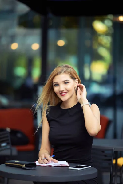 Beautiful girl sitting on the table and do her work, talk at pho — Stock Photo, Image