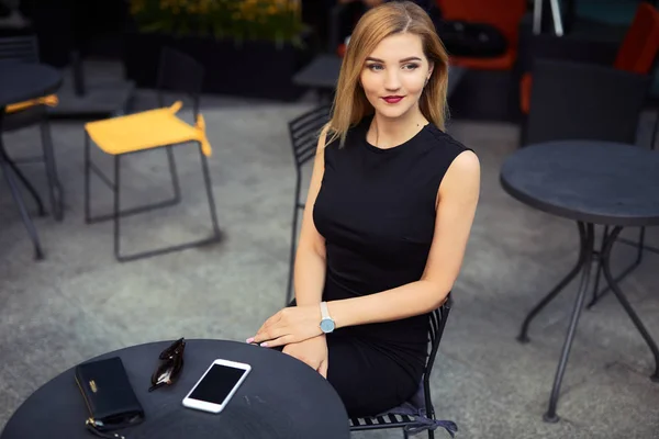 Mooi meisje zittend op de tafel en haar werk doen, praten op pho — Stockfoto