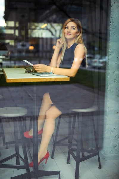 Mooi meisje zittend op de tafel en haar werk doen, praten op pho — Stockfoto