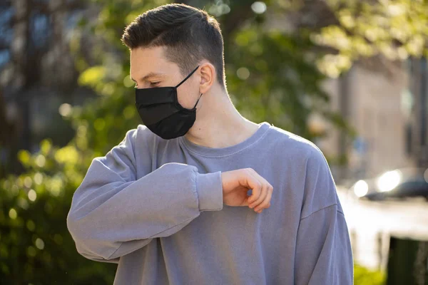 Вірусна маска людини носить захист обличчя для запобігання коронавірусу. Чоловік ходить на вулиці з фоном з зеленого дерева — стокове фото